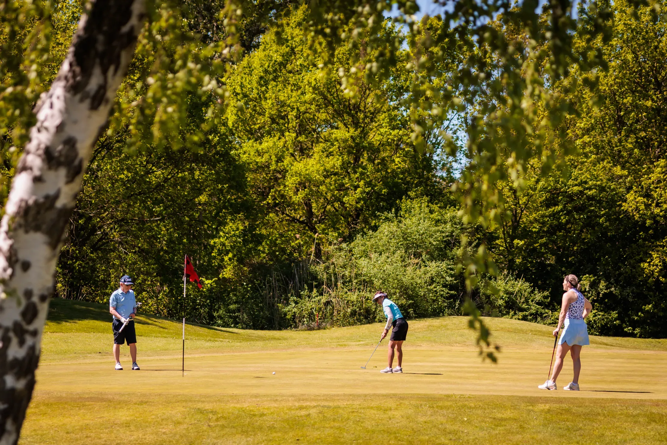 Golfer tee-off bij het water met toeschouwers